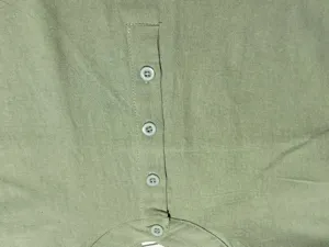 Close-up detail of men's green casual shirt placket with buttons and fine stitching texture.