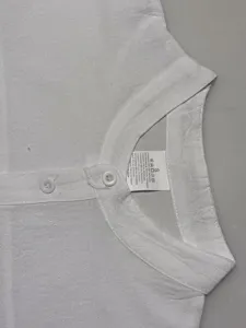Detail shot of men's white linen blend mandarin collar shirt showing buttons and collar.