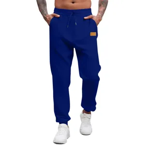 Detailed view of mens blue jogger sweatpants with drawstring waist and decorative leather patch.
