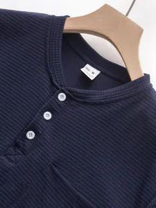 Dark blue waffle knit long sleeve henley shirt detail view showing buttons and collar tag.