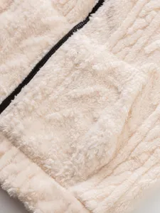 Detailed view of cozy cream sherpa fleece hoodie pocket and zipper. Premium soft fabric texture.