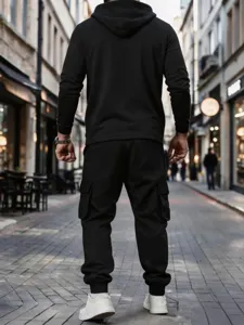 Back view detail of black hoodie and cargo pants streetwear set, outdoor street scene.