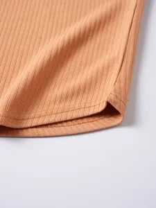 Vista detallada de cerca del dobladillo de la camiseta de punto acanalado, textura fina y costuras.