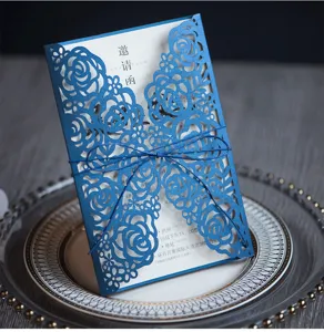 Nahaufnahme einer eleganten blauen lasergeschnittenen Geschäftseinladung mit Rosenmuster