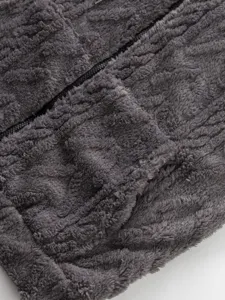 Close up detail view of grey fuzzy fleece winter jacket zipper and pocket texture.