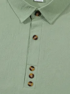 Close-up view of light green mens casual short sleeve shirt collar and textured button placket.