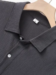 Close-up detail of dark gray short sleeve men's shirt collar texture and button.