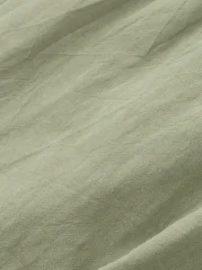 Close-up of breathable cotton linen fabric texture in light green, fine weave detail.