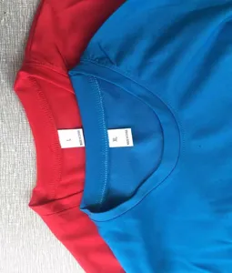 Detail shot showing collar and size tags of red and blue cotton t-shirts, neat knit texture.