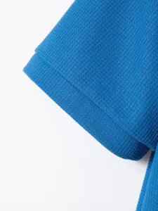 Close-up detail of the blue waffle knit fabric and sleeve cuff, showing fine texture and stitching.