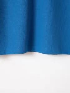 Close-up detail of blue waffle knit fabric, showing fine texture and neat stitching.