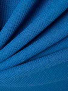 Close-up detail of blue waffle knit fabric showing clear texture and breathable knit structure.