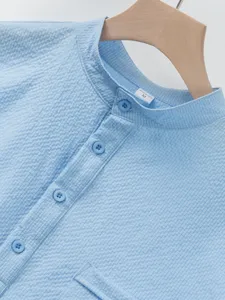 Close-up detail of light blue short-sleeve stand collar shirt with textured pattern.