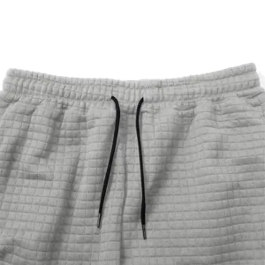Close-up of men's gray waffle knit sweatpants waistband with black drawstring texture detail.