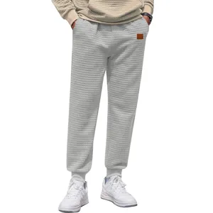 Detailed view of men grey waffle knit joggers casual sweatpants with elastic cuffs and patch.
