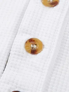 Men's white waffle knit long sleeve shirt detail, textured fabric with brown buttons.