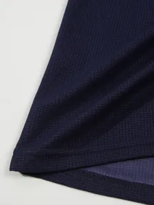 Detail of dark blue men's waffle knit long sleeve t-shirt fabric texture and fine stitching.