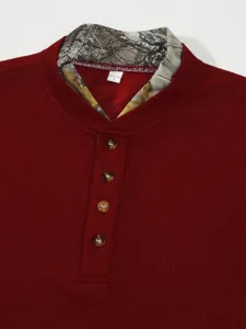 Detailed view of men red waffle knit henley shirt collar featuring camo lining pattern.