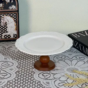European style white ceramic cake stand with relief pattern and wooden base for home decor display.