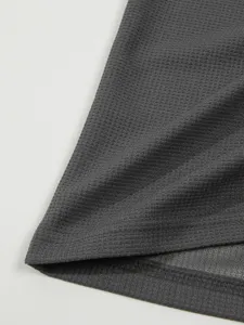 Close-up detail of dark gray waffle knit fabric texture showing hem and fine stitching.