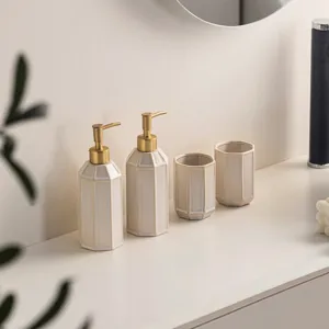 Close-up detail of minimalist ceramic bathroom dispenser set with elegant gold pumps.