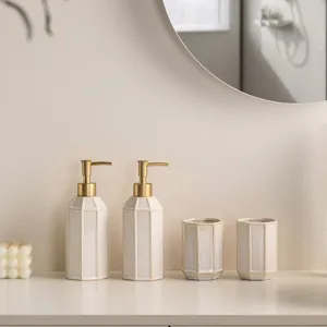 Minimalist ceramic bathroom soap dispenser and tumbler set with gold pump for hotel home.