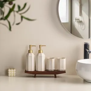 Minimalist ceramic bathroom set with lotion dispensers, tumblers, and a stylish wooden tray.