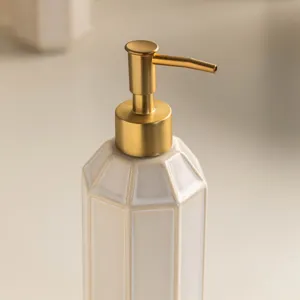 Ceramic soap dispenser detail view, minimalist bathroom lotion bottle with gold pump.