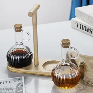 Borosilicate glass oil dispenser bottle with wooden tray and cork stopper for kitchen.