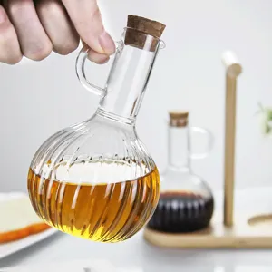 Glass oil bottle with cork stopper, ribbed design and convenient handle for kitchen use.