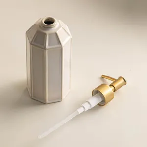Minimalist ceramic soap dispenser detail, elegant octagonal bathroom bottle with gold pump.