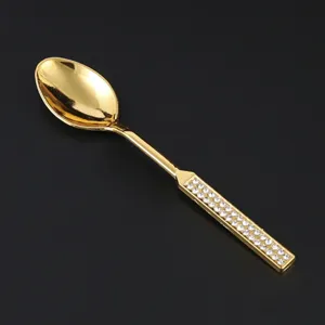 Dettaglio cucchiaino da caffè dorato con manico elegante intarsiato di strass lucidi.