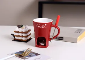 Detailansicht der Keramik Schokoladenfondue Tasse mit Kerze und Gabel, roter Schmelztopf.