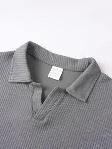 Nahaufnahme Detail des grauen gerippten Strick Herren Polohemdes Kragen und Waschetikett.