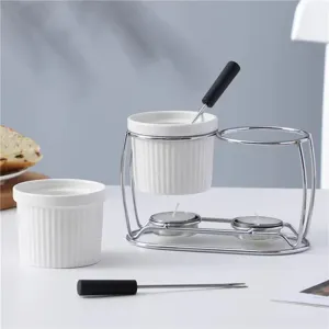 White ceramic chocolate fondue set with metal stand and forks for butter cheese melting.