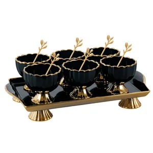 Close-up detail of luxury black and gold ceramic dessert bowls set with matching tray and spoons.