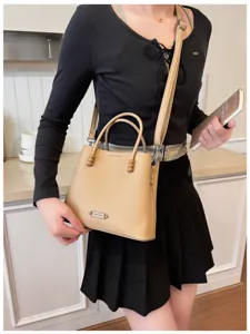 Detailed view of women's trendy light brown leather handbag with beaded handle and shoulder strap.