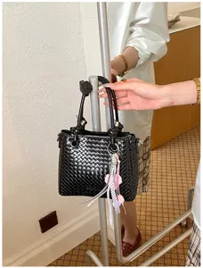 Black woven leather bucket bag for women, stylish minimalist commuter shoulder bag.