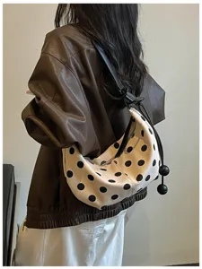 Detailed view of the stylish polka dot shoulder dumpling bag with cute spherical pendant.