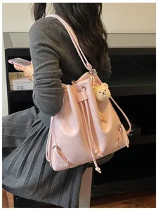 Vista detallada de una elegante mochila saco de cuero PU rosa con dije de oso y cordón.
