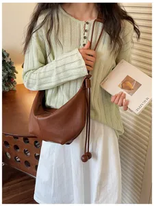 Close-up detail of the brown leather shoulder bag highlighting its soft slouchy shape.