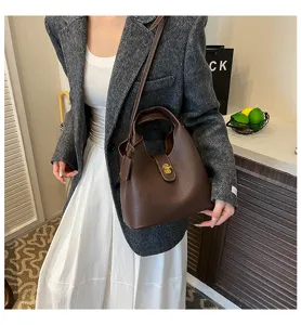 Vintage brown leather handbag for women, stylish bucket bag with lock closure and strap.