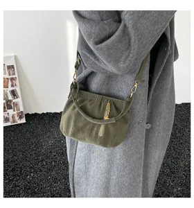 Close-up view of olive green suede shoulder bag with gold chain zipper detail and slim strap.
