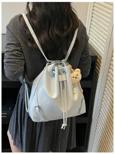 Vista detallada de la mochila de cuero azul claro con cordón, lindo dije de peluche de oso y correas.