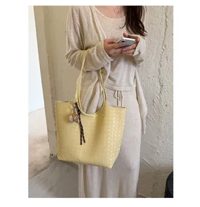 Detailed shot of yellow woven soft leather tote bag, showing intrecciato texture and charm.