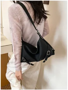 Vue détaillée d'un élégant sac à bandoulière noir pour femme avec boucles et cuir souple.