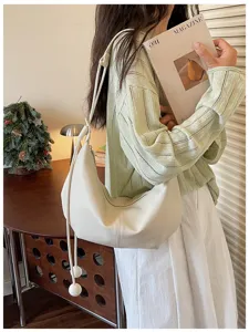 Detail shot of minimalist white hobo shoulder bag with stylish drape strap, casual daily wear look.