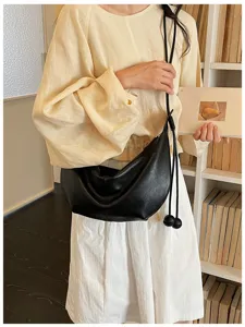 Detailed view of a chic black leather shoulder bag, slouchy dumpling crossbody design for women.