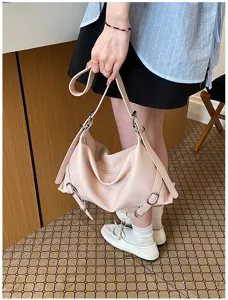 Vue détaillée du sac porté épaule en cuir souple rose avec des boucles en métal élégantes.