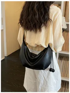 Detail view of a stylish black leather shoulder underarm bag with zipper and tassel charm.